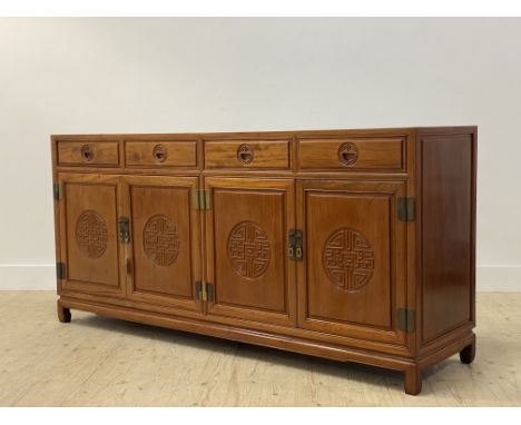 A Chinese hardwood sideboard, the panelled top over four drawers and four carved panel doors, raised on stile supports H87cm,
