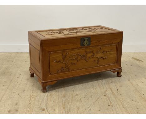 A Chinese hardwood blanket box, the top and panelled front carved with birds and blossom trees, enclosing a camphor wood line