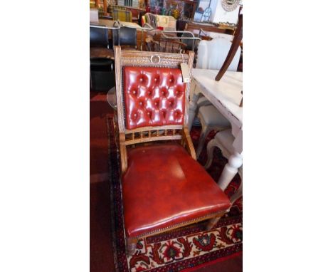 An Edwardian oak chair, with red leather button back upholstery, raised on turned legs 