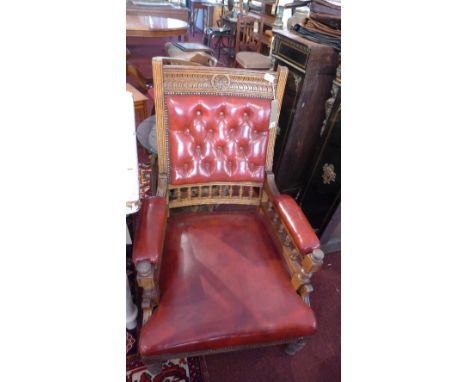 An Edwardian oak armchair, with red leather button back upholstery, raised on turned legs 