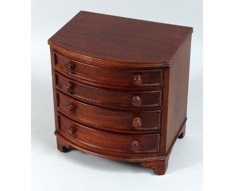 A MINIATURE MAHOGANY BOW FRONT CHEST OF DRAWERS, four long graduated drawers with wooden handles on bracket feet. 8ins high.