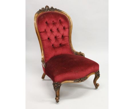 A VICTORIAN WALNUT FRAMED BUTTON BACK ARMCHAIR, on carved cabriole legs with castors.
