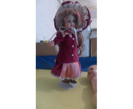 Bonneted AM dressed doll with bisque head on stand and an unclothed early 20th century doll 