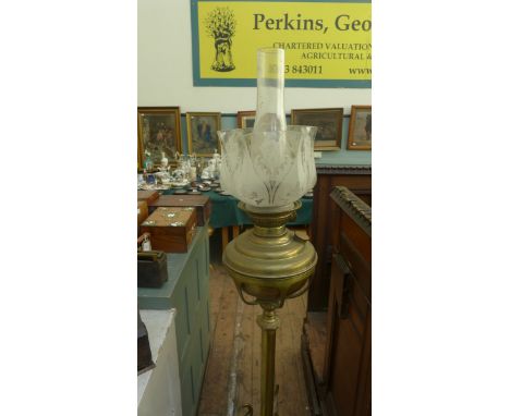Oil lamp with decorative etched glass shade on brass pedestal on three splayed feet