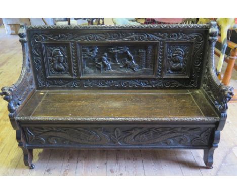 A Victorian Oak Heavily Carved Bench with lift up seat decorated with scene of courting couple, birds to base and lion mask t