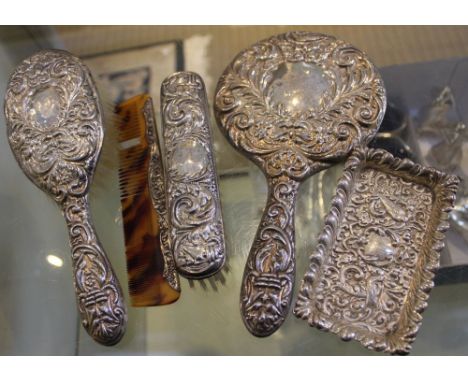 Silver mounted dressing table items, comprising a hand mirror and two brushes with Green Man embossed decoration, together wi