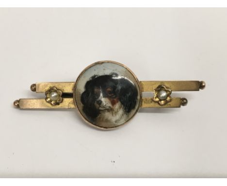 A Edwardian 9 ct gold brooch inset with a small porcelain panel depicting a spaniel flanked by seed pearls