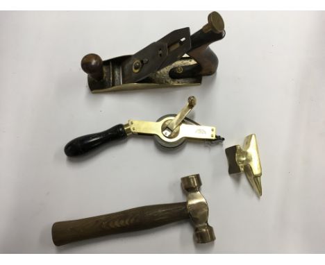A collection of vintage brass tools including Chesterman tape measure, wood plane, hammer and  miniature anvil