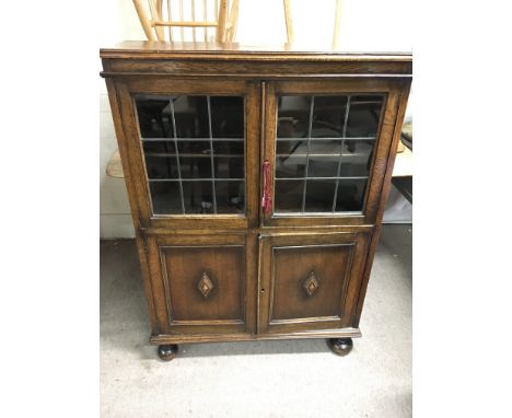 An oak display cabinet with two glass doors and two wooden doors each compartment having one large shelf. Approximately 92cm 