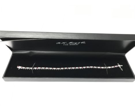 A boxed silver bracelet set with CZ and ruby coloured stones.