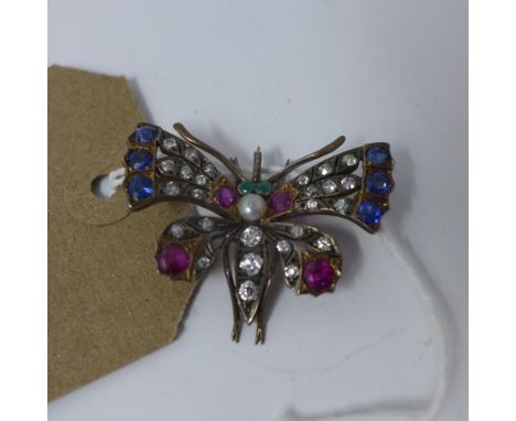 A Continental Austrian yellow metal brooch in the form of a butterfly inset with rubies, sapphires and diamonds, having two e