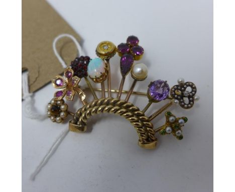 A yellow metal brooch in the unusual form of various hatpins set as a crown, each pin having a different design, brooch inset