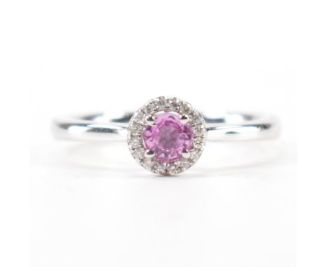 A hallmarked 9ct white gold, pink sapphire &amp; diamond halo ring. The ring having a central round cut prong set pink sapphi