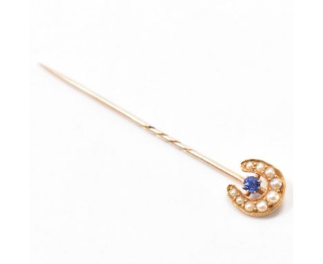 An early 20th Century antique gold, sapphire and seed pearl stick pin. The horse shoe finial being set with graduating seed p