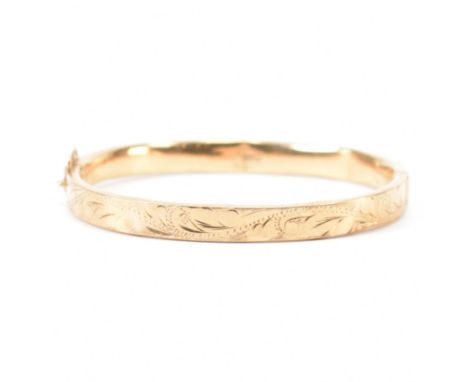A hallmarked 9ct gold bangle having etched decorated half band. Hallmarked Birmingham 1988. Weight 9.04g. AF Dents to band.
