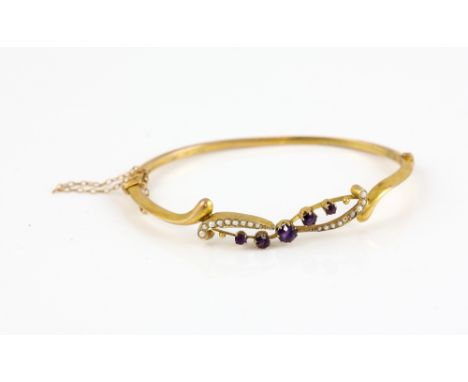 Edwardian oval hinged bangle, set with round cut amethysts and seed pearls, in a wave formation, in 9 ct yellow gold.     CON