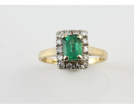 Emerald and diamond ring, central rectangular step cut emerald, estimated weight 0.77 carats, set within a border of round br