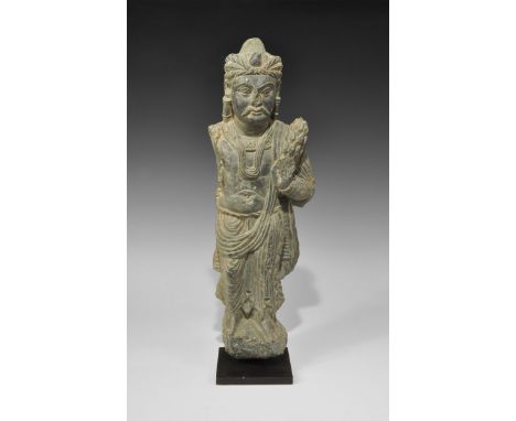 Gandharan Schist Male Statuette 3rd-4th century AD. A carved stone figure of a standing male devotee in loose robe, with garl