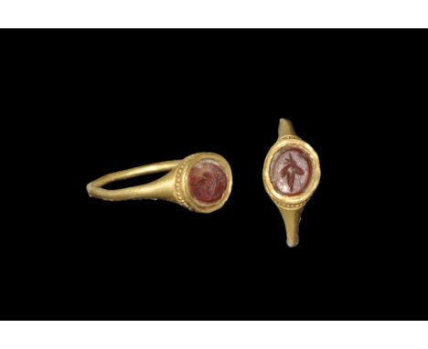 Roman Gold and Garnet Ring with Vine Leaf Intaglio 3rd century AD. A solid gold round-section hoop with expanding shoulders s