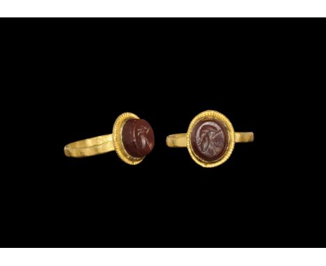 Roman Gold and Carnelian Ring with Helmet Intaglio 3rd century AD. A flat-section hoop with facetted outer face, discoid plaq