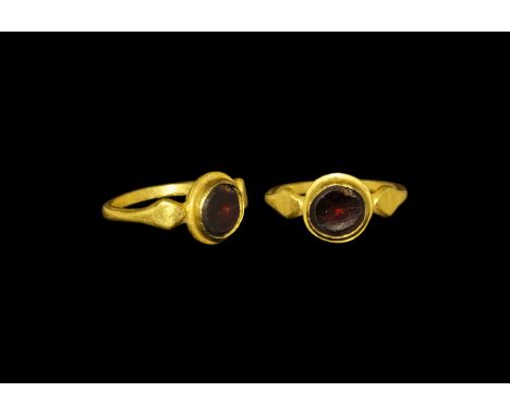 Roman Gold and Garnet Ring 3rd century AD. A round-section hoop with lozengiform shoulders, bowl bezel with discoid cell, ins