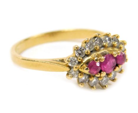 An 18ct gold ruby and diamond ring, with three central rubies in a surround of diamonds, size K, 3.1g.