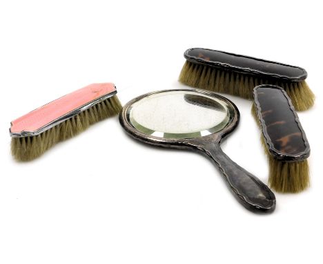 A George V silver and tortoiseshell backed three piece dressing table set, comprising a hand mirror and pair of clothes brush