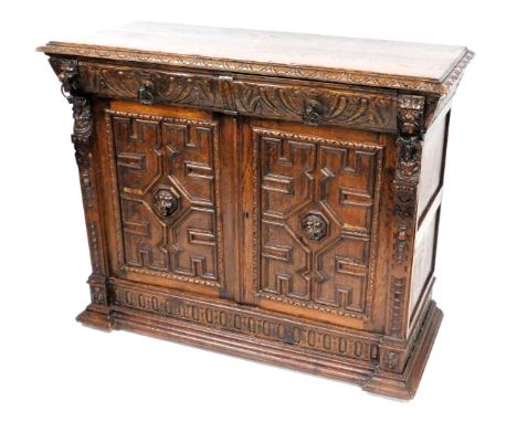A Victorian oak cupboard, with a pair of foliate carved cushion drawers, above a pair of panelled doors centred with lion's h