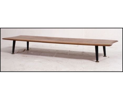 A mid century teak vintage / retro surf board style coffee table raised on tapered ebonised stub legs. Measure: 18cms high x 