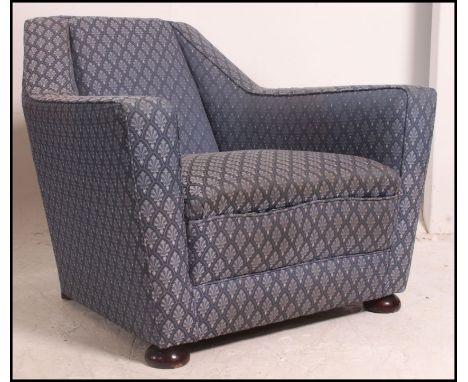 A vintage post war Art Deco club armchair of angular form raised on block feet with blue upholstered fabric.  Measures: 72cms