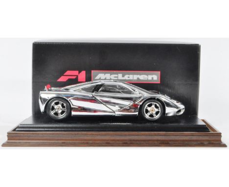 An original boxed 1/18 scale chromium polished diecast model of a F1 McLaren. The model appearing mint housed within a glass 