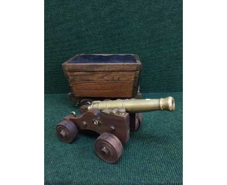 A brass cannon on wooden trolley and a sewing box modelled as a wooden cart 