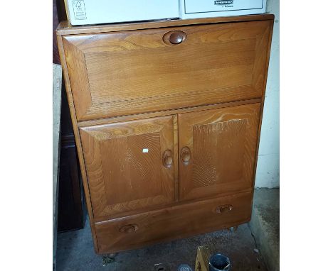 An 82cm Ercol Windsor Model 469 light elm drinks cabinet with fall-front, pair of cupboard door and long drawer under, set on