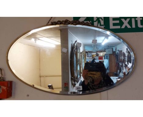 A vintage metal framed bevelled oval wall mirror with applied cast pediment
