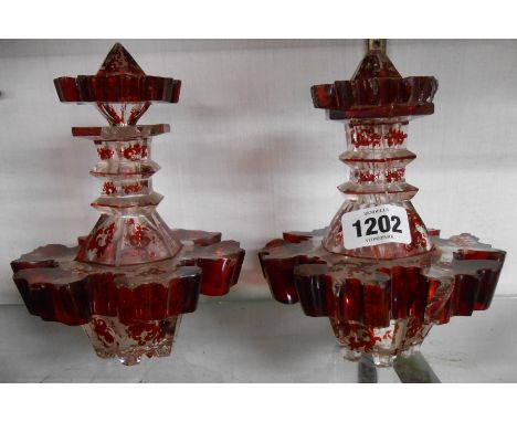 A pair of 19th Century Bohemian ruby overlay glass scent bottles of faceted form with stoppers - a/f