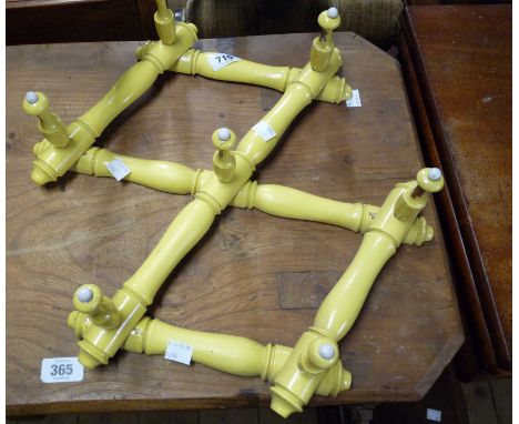 A vintage yellow painted wooden coat rack with white ceramic bosses