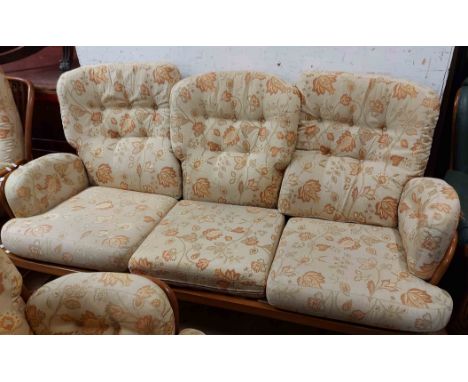 An Ercol three piece suite comprising 1.8m stick back settee and pair of elbow chairs, all with webbed seats and cushions