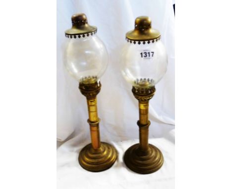 A pair of propelling candlesticks with glass dome covers in the form of an oil lamp
