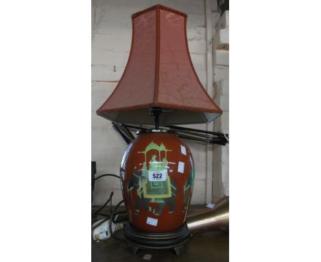 A modern ceramic lamp with elephants and rider decoration on a red ground