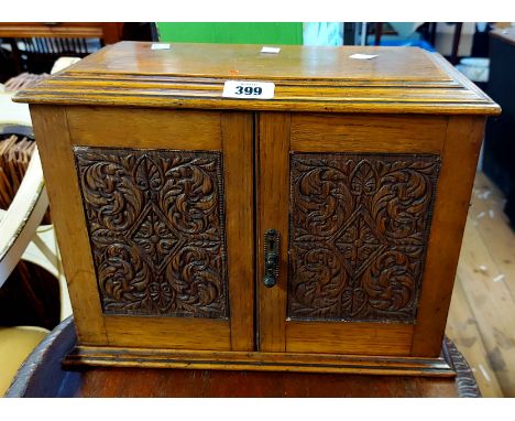 A small vintage oak smoker's cabinet with lift-top and double cupboard enclosing a fitted interior with ceramic tobacco jar a