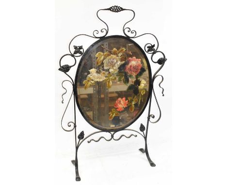 An Art Nouveau wrought iron framed firescreen inset with central oval painted bevelled mirror, height 90cm.