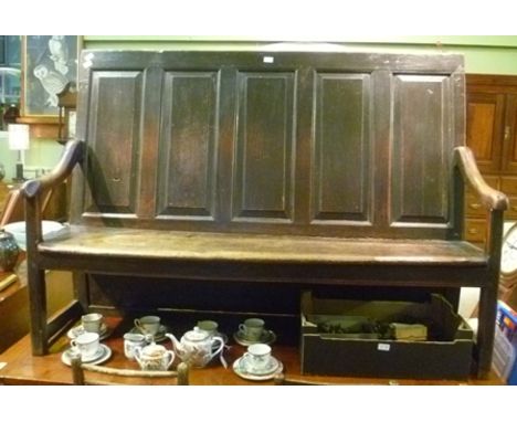 A GEORGE III OAK PANEL BACK BENCH SETTLE having scrolling open arms, plank seat, on chamfered squared fore supports, 1.68m wi