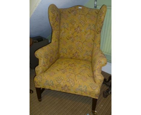 A GEORGE III MAHOGANY FRAMED WINGBACK EASY CHAIR on plain supports and stretchers, upholstered in a mustard ground tapestry e
