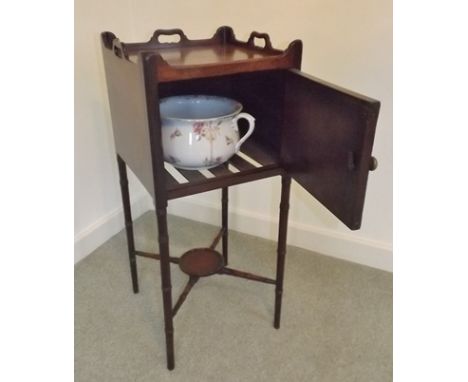 A GEORGIAN MAHOGANY POT CUPBOARD, having shaped gallery top with pierced handles, fitted door (contains chamber pot), on slen