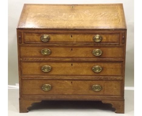 A GEORGE III OAK FALLFRONT WRITING BUREAU opening to reveal a fitted interior of drawers and pigeon holes about a central doo