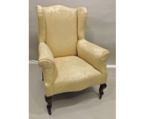 AN EDWARDIAN WING BACK DRAWING ROOM CHAIR raised on cabriole fore supports with ceramic castors, upholstered in pale yellow s