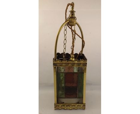AN EDWARDIAN BRASS FRAMED HALL LANTERN with leaded glass panels, stamped brass decorative borders, hoop top with suspension h