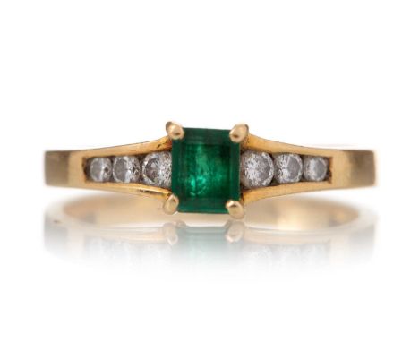 EMERALD AND DIAMOND RING set with a step cut emerald flanked by graduated diamonds, marked 750, size M 1/2, 3g