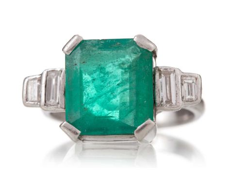 EMERALD AND DIAMOND RING set with a step cut emerald of approximately 3.00 carats, flanked by baguette cut diamonds, to an en