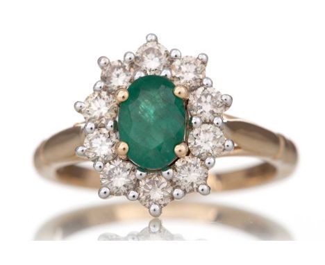 EMERALD AND DIAMOND RING set with an oval emerald of approximately 0.85 carats, within a halo of diamonds totalling approxima